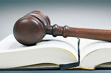 Wooden gavel from the court over the opened law book reflected on white background with space for text. Shallow DOF